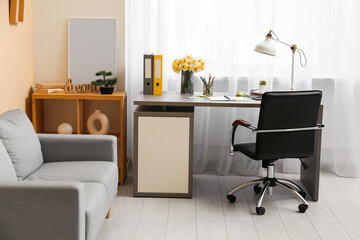 Stylish workplace with lamp, bouquet of narcissus flowers and notebook in office