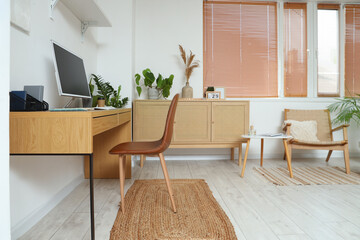 Interior of office with workplace, drawers and green houseplants