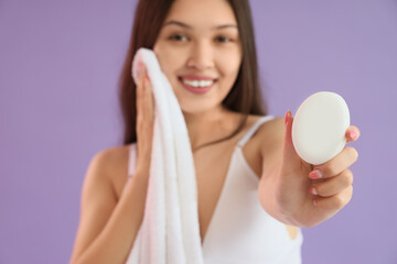 Young Asian woman with soap and towel on lilac background