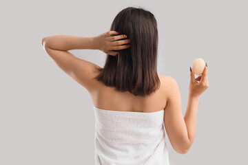 Obraz premium Young woman with soap on light background, back view