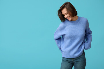 Beautiful young woman in stylish sweater on blue background