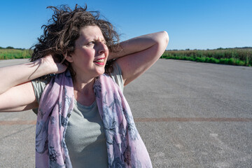 Mujer relajada con los brazos en la nuca en la pista de aterrizaje de un aeropuerto mirando hacia...