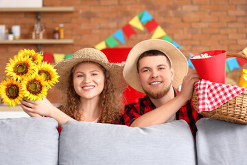 Happy young couple with sunflowers and popcorn at home. Festa Junina celebration