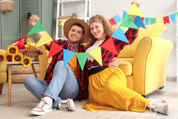Obraz premium Happy young couple with colorful flags at home. Festa Junina celebration