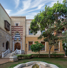 Obraz premium A serene courtyard with Mamluk style architecture surrounds a tranquil fountain under clear skies