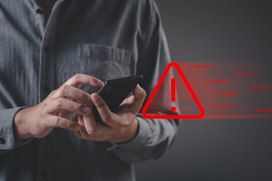 Businessman or User holding smartphone with problem safety security triangle caution warning sign red alarm for notification network error and maintenance concept. warning sign exclamation.