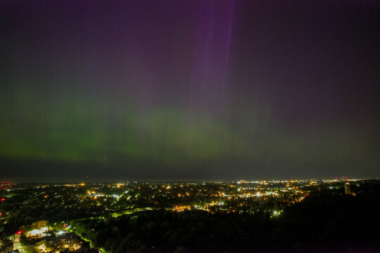An aerial view of the Aurora Borealis over Cleveland, Ohio on May 5th, 2024. The Northern Lights are green near the horizon but became purple higher up. There are bright streaks through the purple