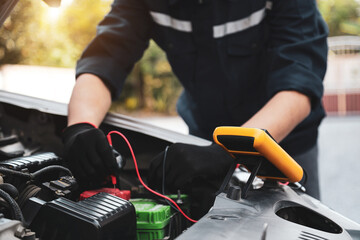 Car mechanic use voltmeter to check voltage battery low energy problem for car care service...