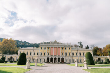 Park with statues in front of the ancient Villa Olmo with empty banners on the facade. Lake Como, Italy