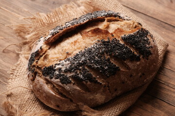 whole wheat rustic sourdough bread on a wooden table. sprinkle black sesame on the surface of the...