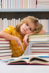 Tired school boy, bored pupil at school. Child not study read book in classroom. Little student read book. School boy reading book in library.