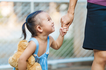 young mom shares a tender moment with her playful, happy Asian two-year-old female toddler, as they...