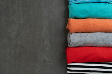 close up of rolled colorful t shirt clothes on pink table background, travel and lifestyle concept