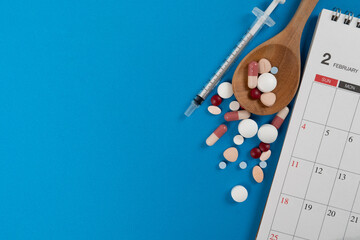 many colorful drug medicines or pill and calendar on the blue table background, healthy and medicine concept