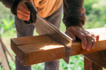 Older man working at home with handsaw. Latino cutting wood and repairing. Carpentry tools.