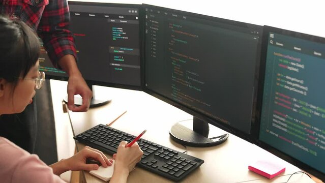 Back end or software developer manager supervising his team on new application program development on debugging and solving complex code algorithms on monitor. Burgeoning