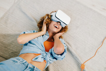 Virtual Reality Joy: A Smiling Woman Enjoying a Futuristic VR Game at Home with VR Glasses on Sofa.