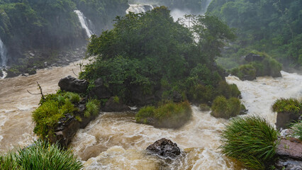 A stormy tropical river. Turbulent streams foam around a small island and rocks in the riverbed....