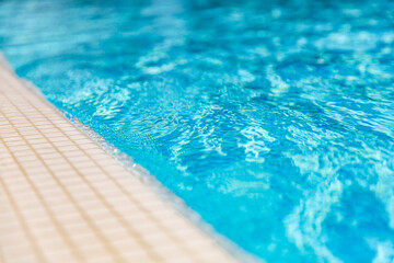 Natural sunlight blur bokeh white marbles closeup of swimming pool edge and clear blue water. New...