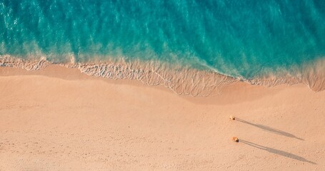 Aerial view amazing beach with couple walking in sunset light close to turquoise sea. Top view of...