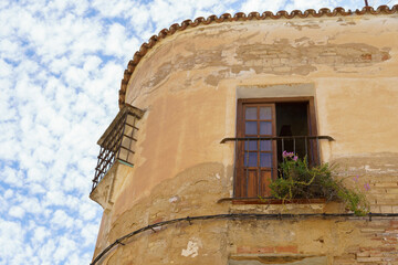 abandoned building with damaged facade and plants on the balcony blue sky with clouds in the...
