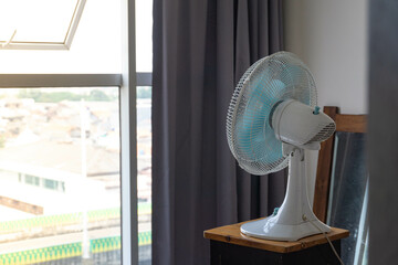 concept of heat wave in the summer, facing desk fan into a windows for better air circulation in apartment
