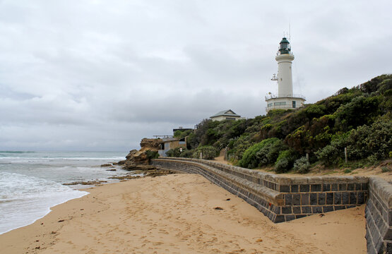 Beach, ocean, shrubs, retaining wall and lighthouse at Queenscliff in Victoria, Australia