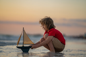Little boy playing with toy sailing boat, toy ship. Travel and adventure concept. Child feeling...