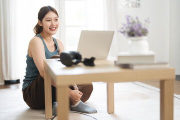 Beautiful young woman working on laptop computer while sitting at the living room, work from home.