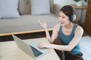Cute woman wear wireless headset video conference calling on laptop computer talk by webcam