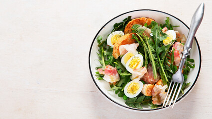 Summer fresh salad from dandelion leaves, eggs, bacon and with bread on light background