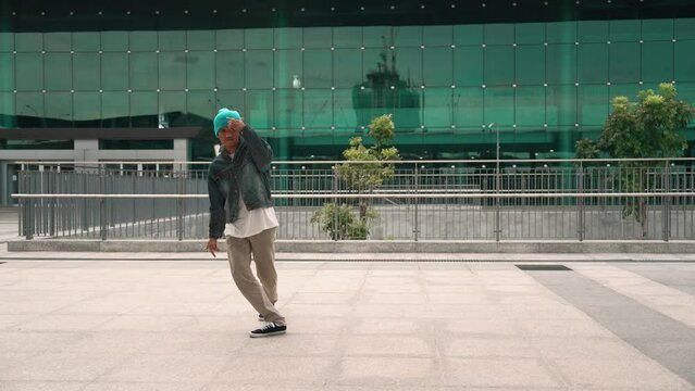 Happy hipster listen to hip hop music from headphone while dancing in lively mood. Professional street dancer perform b boy dancing at outdoor. Outdoor sport 2024. Modern lifestyle. Sprightly.