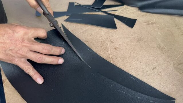 close up handyman cutting leather with scissor for reparing seat