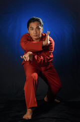 close up of an Asian man in a pencak silat uniform striking a pose ready to attack