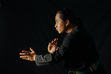 close up of an Asian man in a pencak silat uniform striking a pose ready to attack