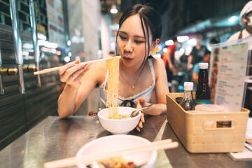 Asian foodie tourist woman eating wonton noodles at China town asia street food night market