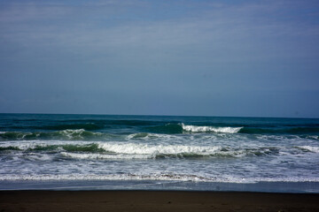 powerful foamy sea waves rolling and splashing over water surface against cloudy blue sky