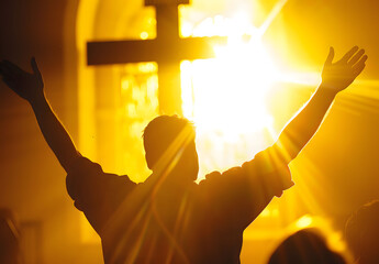 backlit image of a believer hands to heaven worshiping the cross