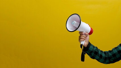 Hand Holding a Megaphone, Isolated on a Yellow Background