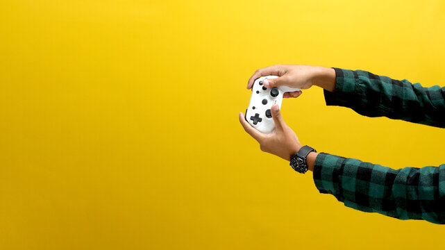Hand holding a gamepad or joystick against a yellow background with empty copy space for text or advertisement