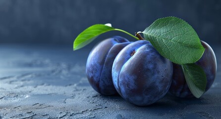 Ripe purple plums with green leaves on a dark background