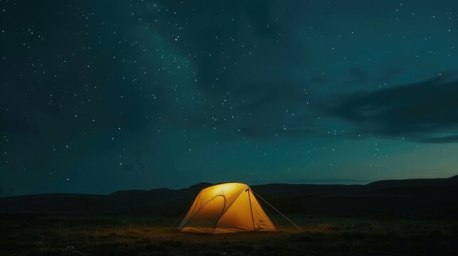 Tent is lit up on the field with a beautiful night sky and stars above