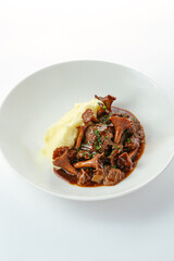 stewed meat with mushrooms and side dish on a plate
