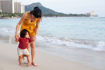 Mom and toddler holding hands walking Waikiki beach © Cavan