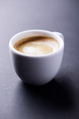 Cup of coffee on dark paper background. Soft focus. Close up. Copy space.