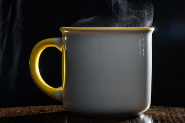 Gorąca herbata paruje z porcelanowego kubka l, para wodna nad kubkiem na czarnym tle 