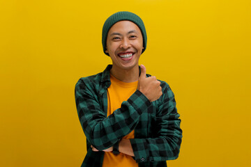 A smiling young Asian man, dressed in casual clothes and wearing a beanie hat, is giving a thumbs...