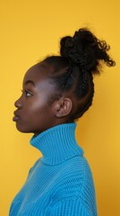 portrait in profile of an African-American girl in a blue sweater on a yellow background.
