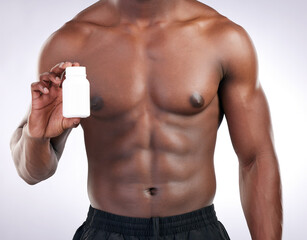 Hands, supplements and pill bottle for man with fitness choice, decision or test by white background. Person, athlete and bodybuilder for drugs, medical or pharma product for muscle growth in studio