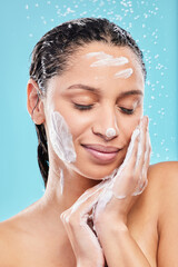 Naklejka premium Beauty, shower and woman with soap in studio for skincare, hygiene or wellness isolated on blue background. Water, foam bath and model cleaning with eyes closed for dermatology, health and wash face